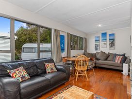 A living room with a sofa and dining table at Coastal Hideaway - Waipu Cove Holiday Home Waipu