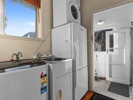 A laundry room with a washing machine, dryer, and sink at Coastal Hideaway - Waipu Cove Holiday Home, Waipu