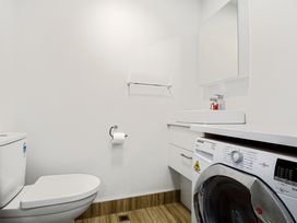 A bathroom with a toilet, sink, and washing machine at Urban Oasis - Christchurch Holiday Home, Christchurch
