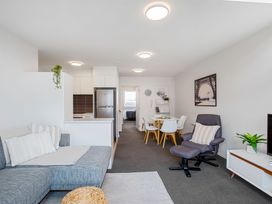 A living room with a sofa and dining area at Urban Oasis - Christchurch Holiday Home in Christchurch