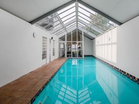 An indoor swimming pool with a glass roof at Urban Oasis - Christchurch Holiday Home in Christchurch