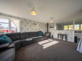 A living room with a sofa and bar stools at Quiet on Quintin - Te Anau Holiday Home Te Anau