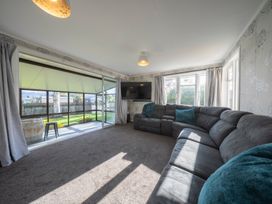 A living room with a sofa and television at Quiet on Quintin - Te Anau Holiday Home in Te Anau