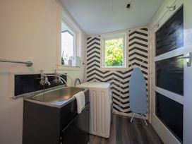 A laundry room with a sink and washing machine at Quiet on Quintin - Te Anau Holiday Home Te Anau