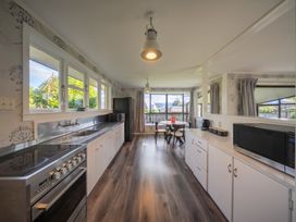 A kitchen with stove, sink, refrigerator and dining table at Quiet on Quintin - Te Anau Holiday Home Te Anau