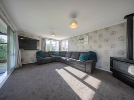 A living room with a sofa and television at Quiet on Quintin - Te Anau Holiday Home, Te Anau