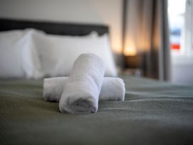 A bed with rolled towels on it at Quiet on Quintin - Te Anau Holiday Home Te Anau