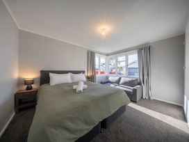 A bedroom with a bed and sofa at Quiet on Quintin - Te Anau Holiday Home Te Anau