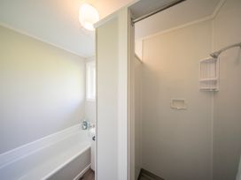 A bathroom with a bathtub and shower at Quiet on Quintin - Te Anau Holiday Home in Te Anau
