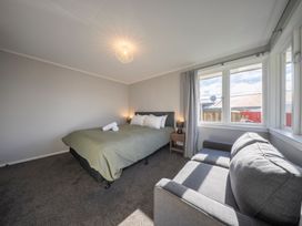 A bedroom with a bed and couch at Quiet on Quintin - Te Anau Holiday Home Te Anau