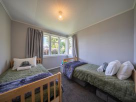 A bedroom with twin beds and a window at Quiet on Quintin - Te Anau Holiday Home Te Anau