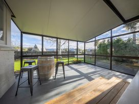 An outdoor patio with stools and a barrel at Quiet on Quintin - Te Anau Holiday Home Te Anau