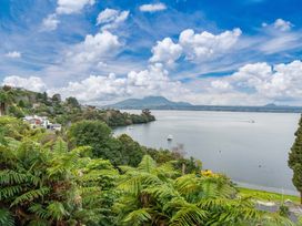 A view of a lake with surrounding trees and mountains at Serenity Above the Lake - Acacia Bay Holiday Home