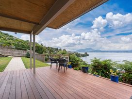 An outdoor area with a deck and chairs overlooking the lake at Serenity Above the Lake - Acacia Bay Holiday Home Acacia Bay