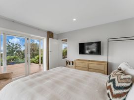 A bedroom with a television and sliding doors at Serenity Above the Lake - Acacia Bay
