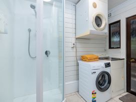 A laundry room with a shower washing machine and dryer at Hawkings Lodge - Kerikeri Holiday home