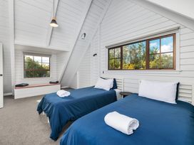 A bedroom with two beds and windows at Hawkings Lodge - Kerikeri Holiday home