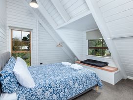 A bedroom with a bed and window at Hawkings Lodge - Kerikeri Holiday home