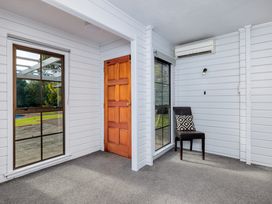 A room with a window, door, and a chair at Hawkings Lodge - Kerikeri Holiday home