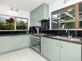 A kitchen with cabinets and appliances at Hawkings Lodge - Kerikeri Holiday home