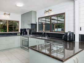 A kitchen with sink, stove, and cabinets at Hawkings Lodge - Kerikeri Holiday home