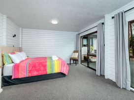 A bedroom with a bed and chair at Hawkings Lodge - Kerikeri Holiday home