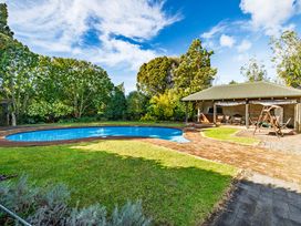 An outdoor area with a swimming pool and patio furniture at Hawkings Lodge - Kerikeri Holiday home