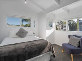 A bedroom with a bed and chair at Whangamata Holiday Home Whangamata