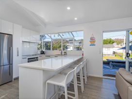 A kitchen with bar stools and appliances at Whangamata Holiday Home in Whangamata