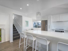 A kitchen with a countertop and stools at Whangamata Holiday Home in Whangamata