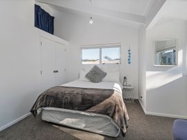 A bedroom with a bed and mirror at Whangamata Holiday Home Whangamata