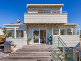 An outdoor view of a house with stairs and a barbecue grill at Whangamata Holiday Home in Whangamata