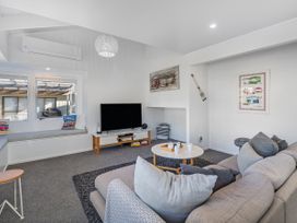 A living room with a sofa and television at Whangamata Holiday Home in Whangamata