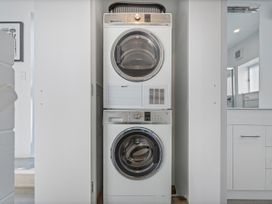 A stacked washing machine and dryer in a laundry room at Whangamata Holiday Home in Whangamata