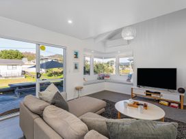 A living room with a sofa and television at Whangamata Holiday Home in Whangamata