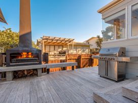 An outdoor patio with a barbecue grill and fireplace at Whangamata Holiday Home in Whangamata