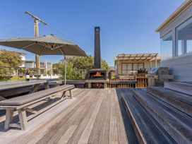 An outdoor area with a table, benches, and a fireplace at Whangamata Holiday Home in Whangamata