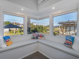 A conservatory with cushions on a seat at Whangamata Holiday Home in Whangamata