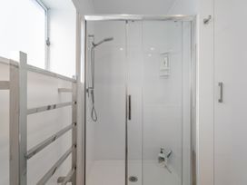 A shower with sliding doors and towel rail at Whangamata Holiday Home in Whangamata