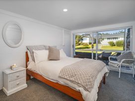 A bedroom with a bed and a nightstand at Whangamata Holiday Home in Whangamata