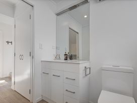 A bathroom with a sink, toilet and mirror at Whangamata Holiday Home in Whangamata