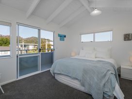 A bedroom with a bed and sliding door at Whangamata Holiday Home in Whangamata