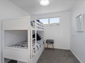 A bedroom with a bunk bed and a bedside table at Whangamata Holiday Home in Whangamata