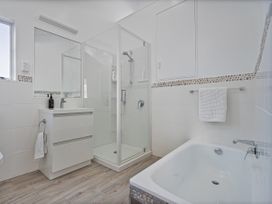 A bathroom with a shower and bath tub at Whangamata Holiday Home in Whangamata
