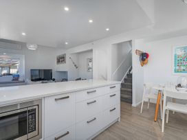 A kitchen with a microwave, television, and dining area at Whangamata Holiday Home in Whangamata