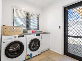 A laundry room with washing machine and dryer at Sunbrae Sands - Mount Maunganui