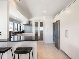 A kitchen with a countertop and bar stools at Sunbrae Sands - Mount Maunganui Holiday Homes