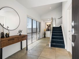 An entrance hall with a staircase and a console table at Sunbrae Sands - Mount Maunganui