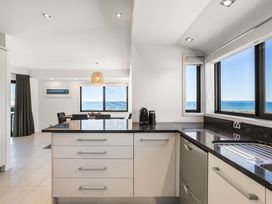 A kitchen with a dishwasher and windows overlooking the ocean at Sunbrae Sands - Mount Maunganui