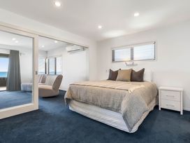A bedroom with a bed and chair at Sunbrae Sands - Mount Maunganui Holiday Homes, Mount Maunganui